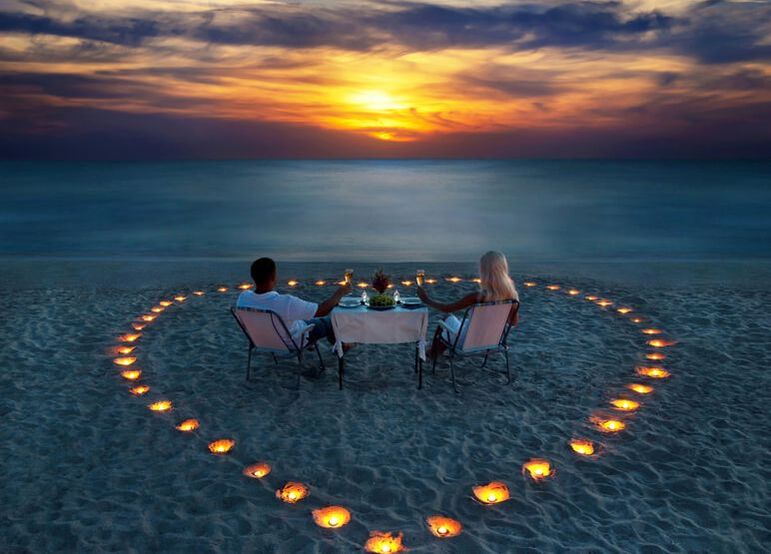 couple on beach at sunset having romantic dinner